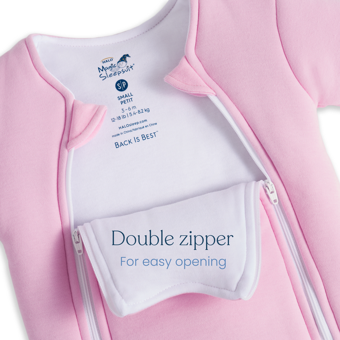 A close-up of Baby Merlin's Magic Sleepsuit® 100% Cotton by HALO in pink with white lining, featuring a double zipper and an easy-open flap—a cozy, convenient sleepwear choice for babies.