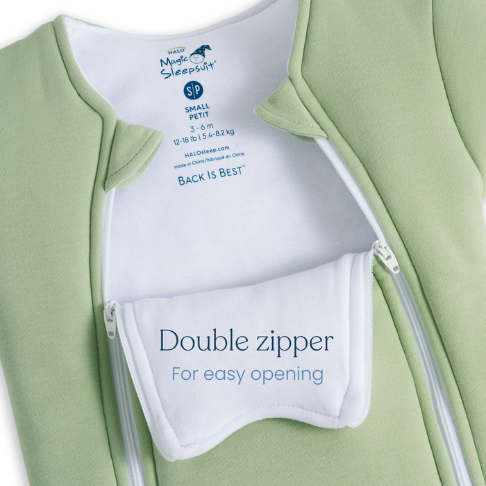 A close-up of a light green Baby Merlin's Magic Sleepsuit® 100% Cotton by HALO, featuring two partially open zippers and a white flap reading "Double zipper for easy opening" in blue text—ideal for swaddle transition.