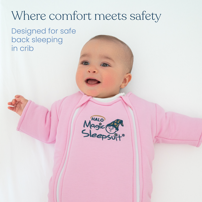 A baby in a pink Baby Merlin's Magic Sleepsuit® 100% Cotton by HALO, featuring a magic sleep hat graphic. Designed for safe back sleeping in the crib—perfect comfy and safe sleepwear for peaceful nights.