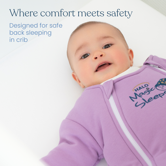 A baby in a lavender Baby Merlin's Magic Sleepsuit® 100% Cotton by HALO lies on their back in a crib. Text: Where comfort meets safety. The ideal swaddle transition for better sleep and safe back sleeping in the crib.