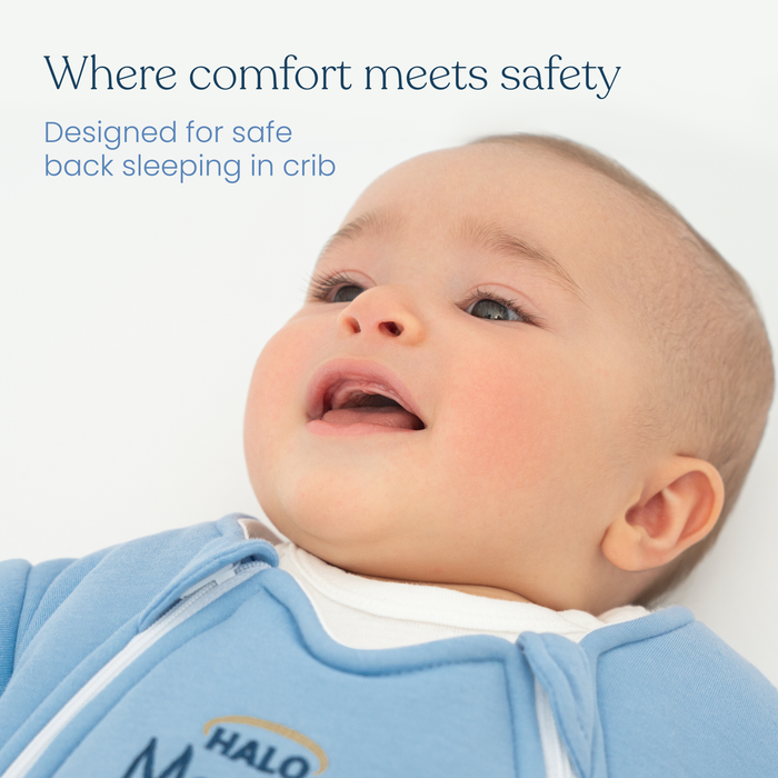 A baby in the Baby Merlin's Magic Sleepsuit® 100% Cotton by HALO lies on their back, looking content. Text reads: Where comfort meets safety. Perfect for swaddle transition and safe crib sleeping.
