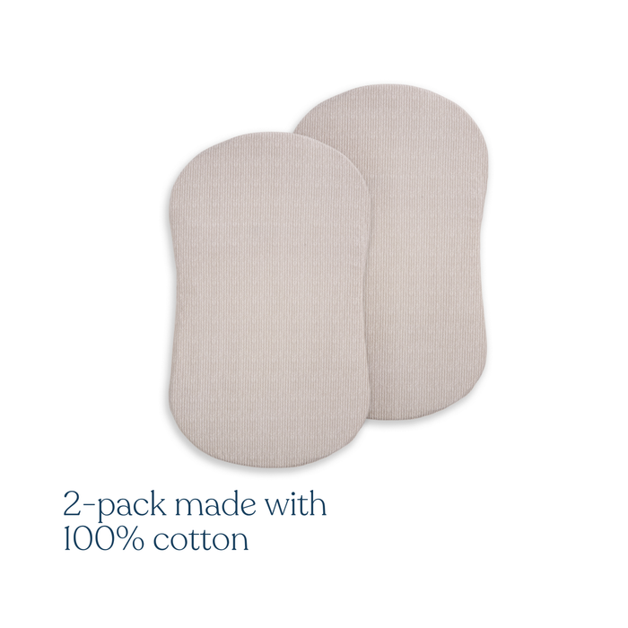 Two beige oval pads, resembling HALO BassiNest® Fitted Sheet 100% Organic Cotton 2-Pack, are side by side on a white background. Lower left text reads, "2-pack made with 100% organic cotton.