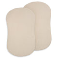 Two beige, oval-shaped BassiNest® Fitted Sheets by HALO overlap on a white background. Made from 100% organic cotton muslin, this 2-pack looks soft and breathable—ideal for a comfortable nursery.