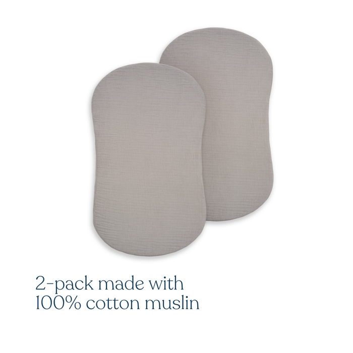 Two light gray, oval BassiNest® Fitted Sheets by HALO are shown overlapping. Text below: 2-pack made with 100% organic cotton muslin—breathable and ideal for use as crib sheets or HALO BassiNest fitted sheets.