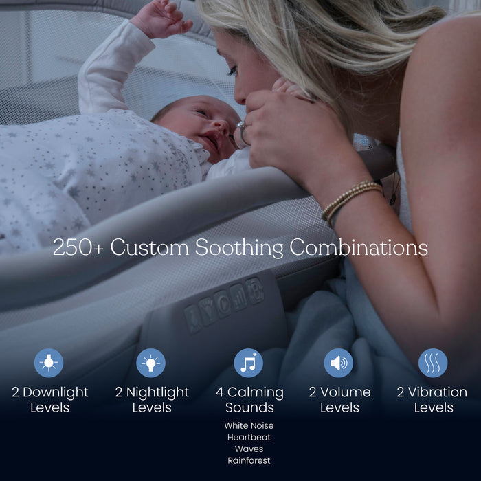 A woman smiles, leaning over her baby resting in the HALO BassiNest® Soothing Swivel Sleeper 3.0 Bassinet, which features 2 downlight and nightlight levels, 4 soothing sounds, 2 volume levels, and 2 vibration settings for comfort.
