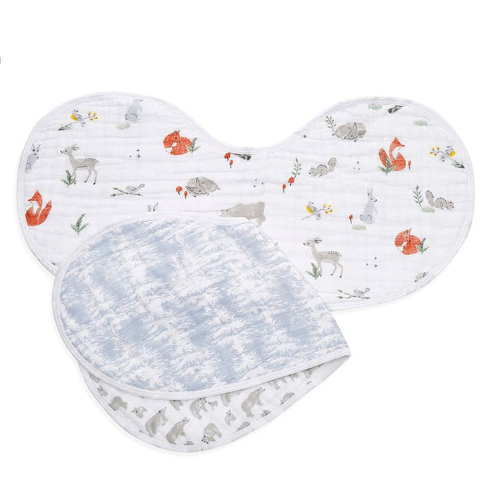 The aden + anais boutique 100% cotton muslin burpy bibs 2 pack showcases two designs: one fits over the shoulder with a woodland animal print featuring foxes, rabbits, and bears; the other has a luxurious cloud-like sky design in blue and white with a subtle animal pattern beneath.
