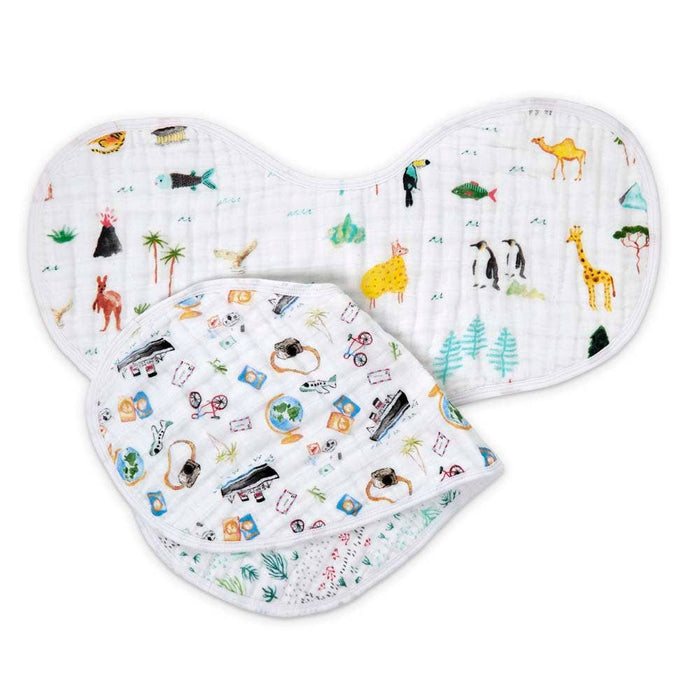 The aden + anais boutique 100% cotton muslin burpy bibs 2 pack includes two white, soft, lightweight, and absorbent bibs. One features colorful animals like a giraffe and camel; the other showcases travel-themed designs with suitcases and globes.