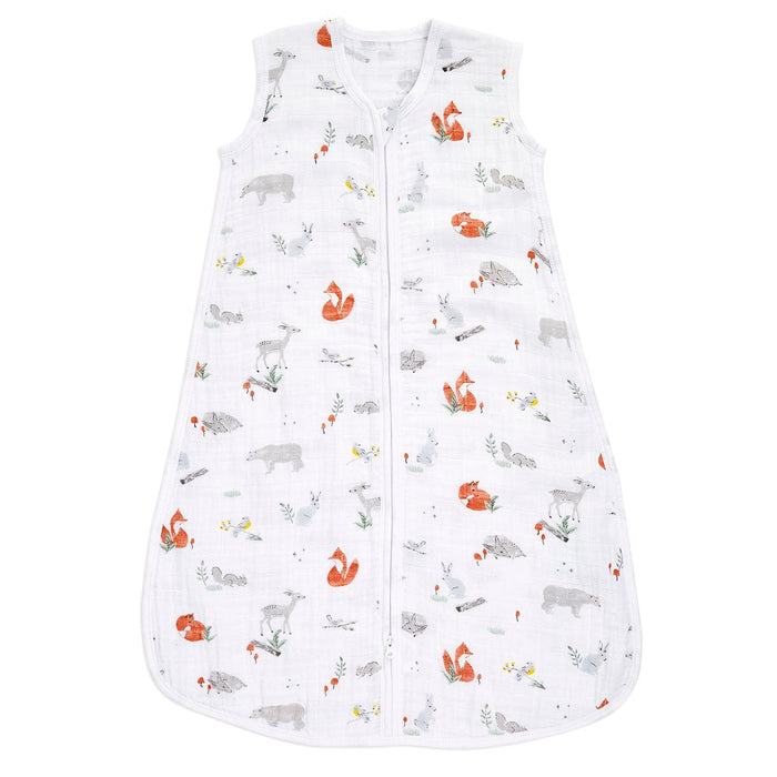 The aden + anais boutique 100% cotton muslin light sleep sack TOG 1.0 is sleeveless, white, and has a central zipper. It features playful illustrations of foxes, deer, and bears with subtle plants and flowers in muted colors for a luxurious finish.