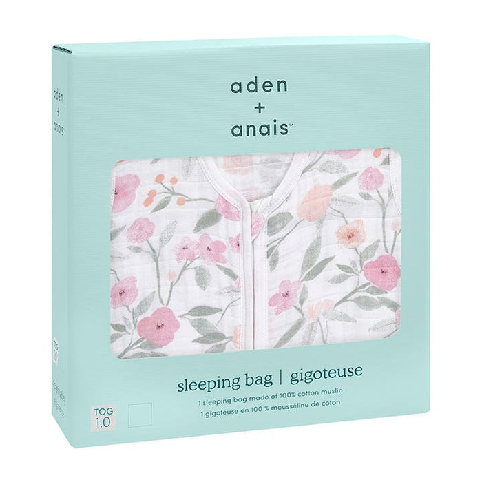 A light blue box contains an aden + anais boutique 100% cotton muslin sleep sack, adorned with pink and peach floral patterns. The packaging highlights its breathable material and TOG 1.0 warmth rating.
