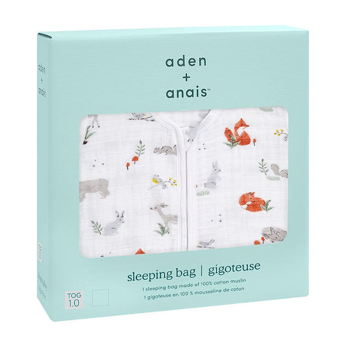 The boutique aden + anais cotton muslin light sleep sack arrives in mint green packaging. Its white fabric features animal and plant illustrations, including a fox, rabbit, and squirrel. Made from breathable cotton muslin with a TOG of 1.0, it offers a luxurious touch for any nursery.