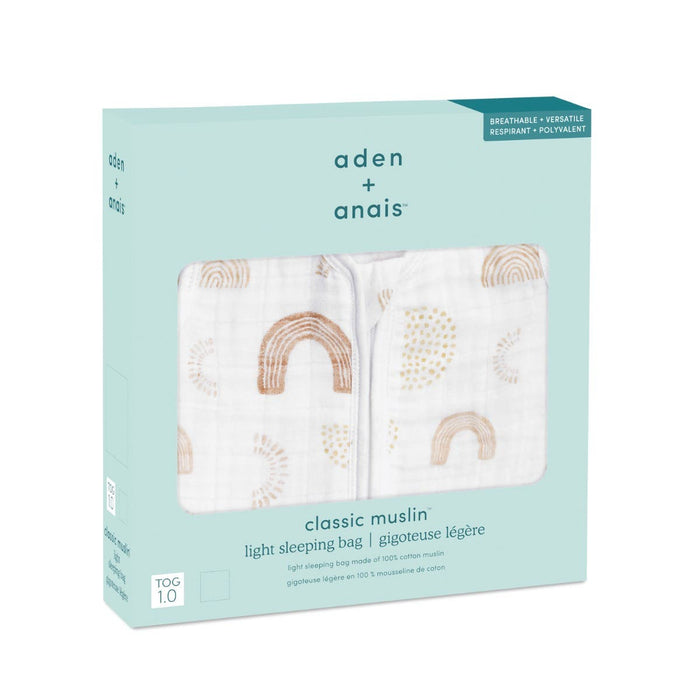 The teal box presents aden + anais boutique 100% cotton muslin light sleep sack, TOG 1.0, featuring a pattern of beige and brown rainbows. Crafted from breathable cotton muslin, it highlights versatility and offers a premium sleeping bag experience.