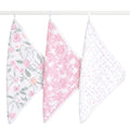 Three aden + anais boutique 100% cotton muslin oversized washcloths hang from a rod: one with a pink and green floral pattern ideal for delicate skin, another featuring pink with white floral designs, and the third is white adorned with small pastel dots, all ensuring comfort during tender moments.