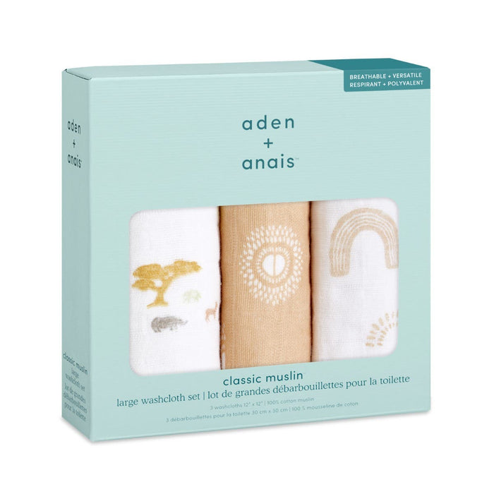 A box of aden + anais boutique 100% cotton muslin oversized washcloths includes three soft-colored washcloths with designs of abstract trees, a sun, and a rainbow. The packaging emphasizes their breathable, absorbent layers and versatile fabric.