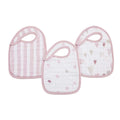 The aden + anais boutique 100% cotton muslin snap bibs 3 pack includes three absorbent bibs with soft pink trim: one with stripes, another with dots, and the third adorned with hearts and arrows on a white background, all featuring an adjustable fit for comfort.