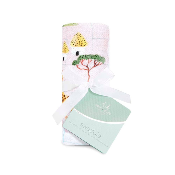 A boutique 100% cotton muslin swaddle blanket by aden + anais is rolled up and tied with a white ribbon. Featuring colorful trees and giraffes, its known for its absorbency and breathable fabric, with a green/white tag labeled swaddle.