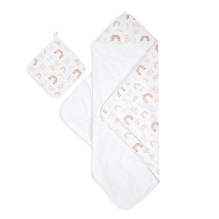 The aden + anais boutique set includes a charming white hooded cotton muslin towel and washcloth, featuring rainbows and abstract shapes in soft colors. The oversized towel has a cozy interior, while the matching square washcloth complements it beautifully.