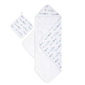 The aden + anais boutique 100% cotton oversized muslin backed towel + washcloth set showcases a delightful pattern of blue and green dinosaurs, with the towel and hood unfolded and the washcloth displayed above to reveal the matching designs.
