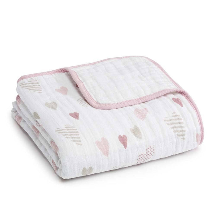 The aden + anais boutique cotton muslin dream blanket is a soft, white folded design made from 100% cotton muslin, with pink trim and patterns of pink and beige hearts, offering comfort and breathability for your little one.