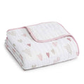 The aden + anais boutique cotton muslin dream blanket is a soft, white folded design made from 100% cotton muslin, with pink trim and patterns of pink and beige hearts, offering comfort and breathability for your little one.