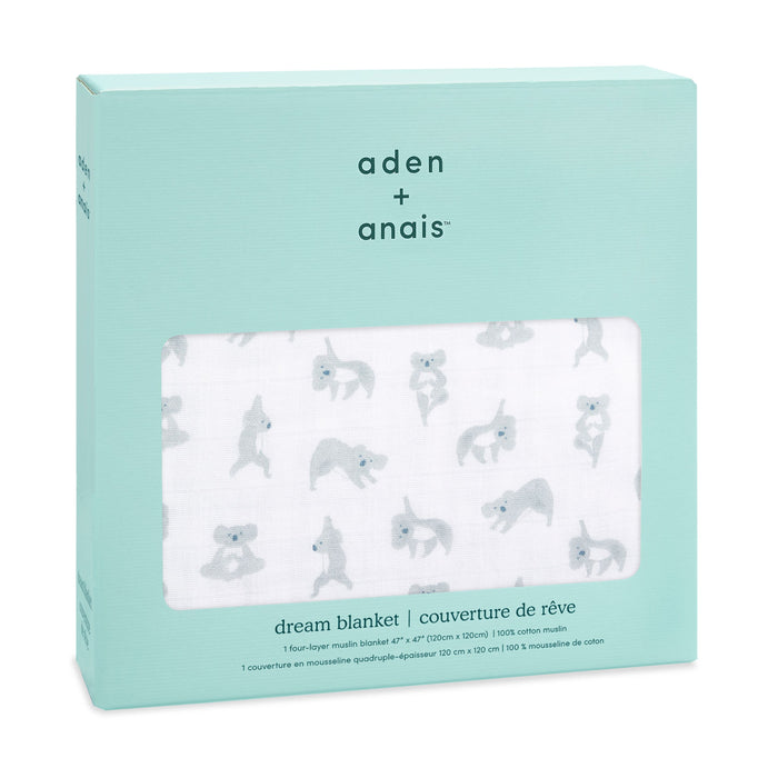 The image shows an aden + anais boutique cotton muslin dream blanket in a light teal package with a clear window displaying small gray koalas. The text highlights its a breathable cotton muslin blanket, measuring 120x120 cm.