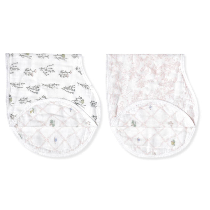 The aden + anais boutique silky soft burpy bib 2 pack includes two quilted cloth bibs with floral designs—one in grey, the other in light pink with leaf patterns. These stylish and absorbent bibs feature round neck openings and adjustable snaps for functionality.