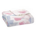 The aden + anais boutique silky soft muslin dream blanket features folded, lightweight bamboo-infused viscose fabric with pastel watercolor-like patterns in pink, blue, and white, offering a cozy yet cool touch perfect for nursery decor or a babys crib.