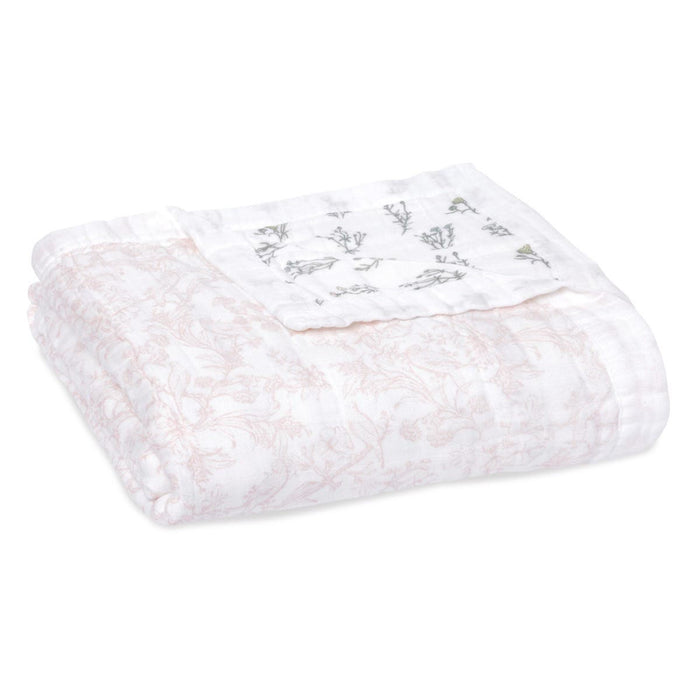The aden + anais boutique silky soft muslin dream blanket offers cozy warmth with subtle floral patterns in light pink and darker motifs. Made from bamboo-infused viscose, this folded white quilt promises a silky touch for comfort seekers.