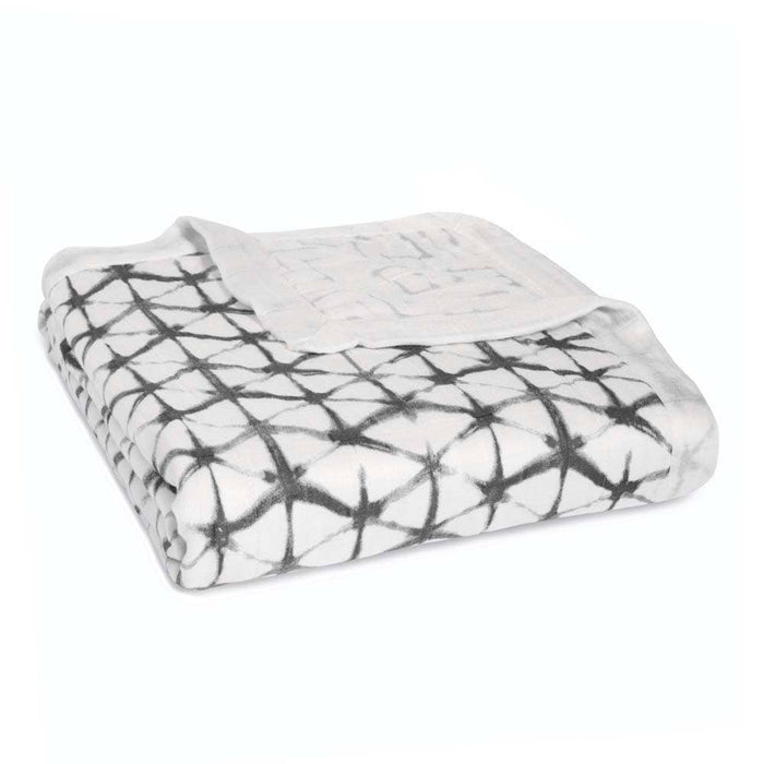 A folded aden + anais boutique silky soft muslin dream blanket features a black and white geometric pattern on a light background, set against a plain white backdrop.
