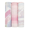 Three rolls of fabric from aden + anais stand together: the left with a pastel watercolor pattern, the middle in pink and white stripes, and the right with a swirling pink, white, and blue design. Crafted from bamboo-infused viscose, they are light and luxurious.