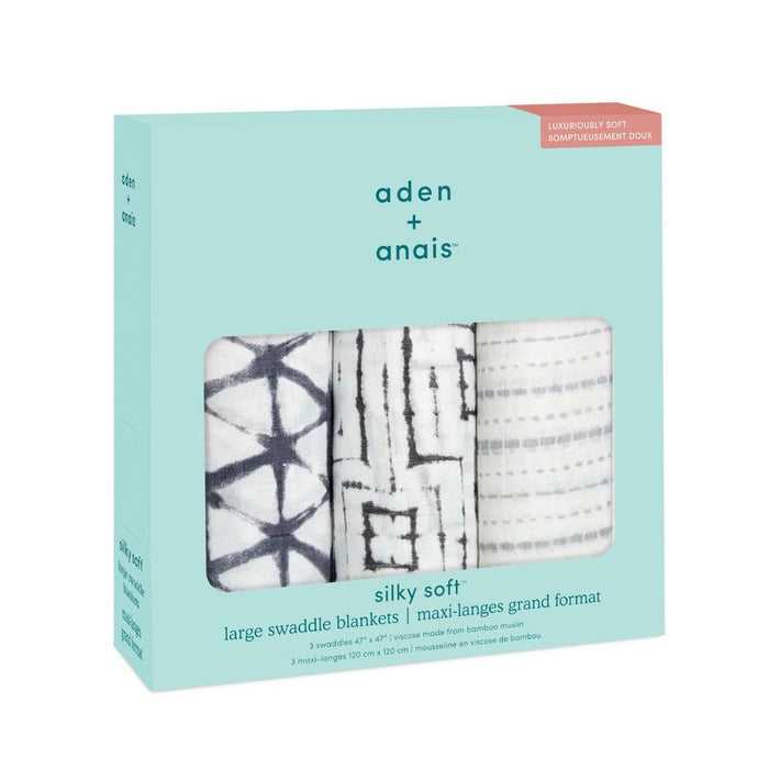 The aden + anais boutique silky soft swaddle blanket 3 pack features three bamboo-infused viscose blankets with unique patterns: black geometric shapes, a black grid, and black dots on white. They come elegantly packaged in a soothing light blue box.