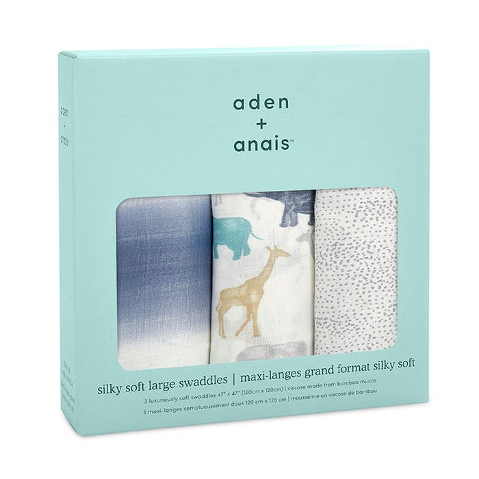 Three aden + anais boutique silky soft swaddle blankets come in a turquoise box, crafted from bamboo-infused viscose. Designs include a blue sky gradient, safari animals, and grey dots. The box includes English and French text specifying the size and material.