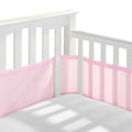 A white crib with slatted sides displays attached light pink HALO Breathable Mesh Crib Liners for a full-sized crib. Built to meet infant bedding safety standards, the empty crib shows gentle sunlight shadows on the white mattress.