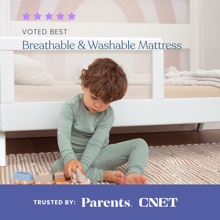 A young child in green pajamas sits on a rug playing with wooden toys before a white crib. Text reads: “HALO DreamWeave™ Breathable Crib Mattress—voted Best Breathable & Washable, trusted by Parents, CNET, and GREENGUARD Gold certified.”.
