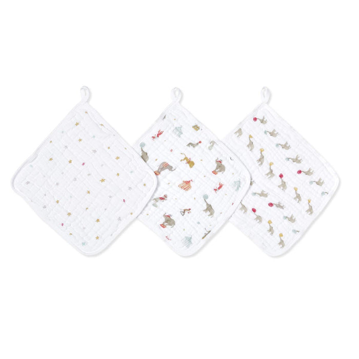 The aden + anais essential cotton muslin washcloths 3 pack includes three white cloths with loop hangers: one with colorful stars, another with playful animals and musical notes, and a third featuring animals with balloons and stars. Each has absorbent layers ideal for delicate skin.