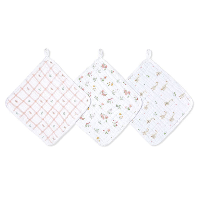 The aden + anais essential cotton muslin washcloths 3 pack includes three soft, square cloths with hanging loops; one in pink checkers, another in floral, and the last featuring charming small animals on absorbent layers—ideal for delicate skin.