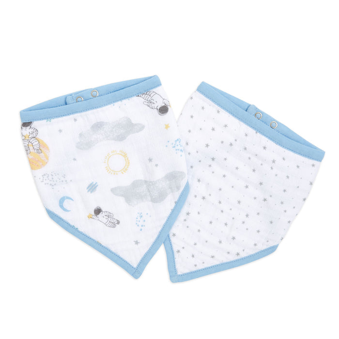 The aden + anais essentials cotton muslin bandana bibs 2 pack includes two adjustable bibs with snap closures: one with astronauts, clouds, and a sun on blue trim; the other features small grey stars on white.