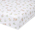 Close-up of the aden + anais essentials cotton muslin crib sheet, featuring a white, rectangular design with a floral pattern of small pink and yellow flowers and green leaves. The fabric looks soft and textured, similar to delicate nursery prints.
