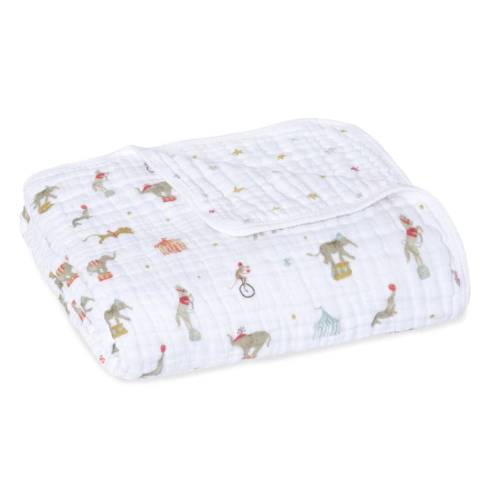 The aden + anais essentials cotton muslin dream blanket showcases a folded design with whimsical circus patterns of elephants, seals, and monkeys. This cozy cloud-themed blanket features a mix of muted colors and scattered small stars for added charm and comfort.