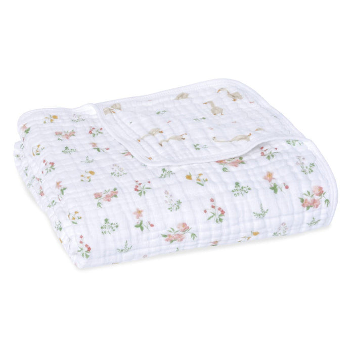 The aden + anais essentials cotton muslin dream blanket, in white, unfolds a warm and cozy ambience with a delightful floral and animal print of delicate pink flowers on textured cotton muslin.
