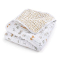 The essentials cotton muslin dream blanket by aden + anais is perfect for tummy time, featuring a cozy, enchanting animal and nature print with lions, turtles, and trees in muted hues. The reverse side has a delightful yellow scattered leaf pattern.