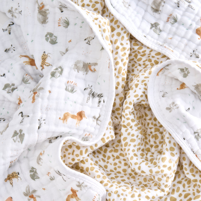 A close-up of aden + anais essentials cotton muslin dream blankets, featuring cozy designs with small animal illustrations or a white and gold spotted pattern—a perfect setting for tummy time.