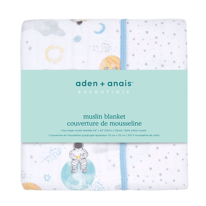 The aden + anais essentials cotton muslin dream blanket, wrapped with a blue paper band, is cozy for tummy time and features charming astronaut, planet, and star designs on a white background.