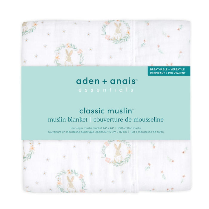 A packaged aden + anais essentials cotton muslin dream blanket with a rabbit and wreath pattern, labeled classic cotton muslin. Its a four-layer 100% cotton blanket, soft as a cozy cloud, measuring 44 x 44.