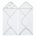 The aden + anais essentials cotton muslin hooded towels 2 pack includes two white plush cotton terry towels with gray edges. The left towels muslin hood has silver stars, and the right one features silver polka dots. Both are unfolded with hoods at the top.