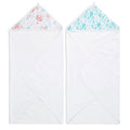 Two essentials cotton muslin hooded baby towels from aden + anais are displayed side by side. The left towel features a pink floral hood, while the right one has a blue and green leaf design. Both white towels are absorbent and folded neatly into triangles.