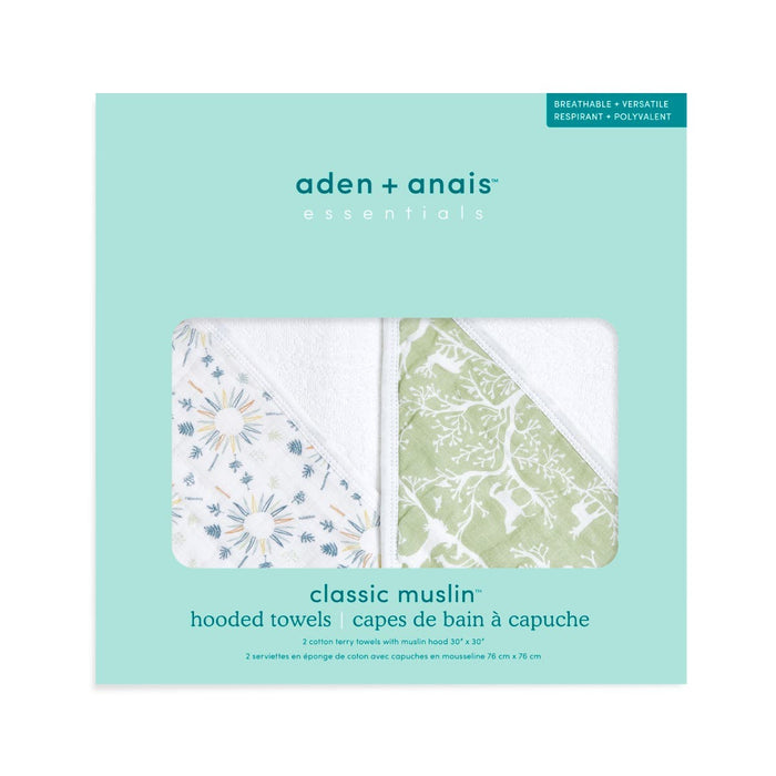 Packaging for aden + anais essentials cotton muslin hooded towels 2 pack features two absorbent designs: one with blue floral patterns and the other with a green forest motif, crafted from cotton terry for optimal comfort and style.