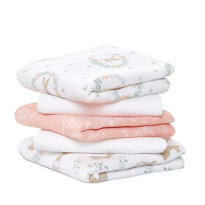 The aden + anais essentials cotton muslin musy squares 5 pack includes four 100% cotton baby blankets featuring pastel floral and animal patterns in white, pink, and soft green, perfect for baby essentials.
