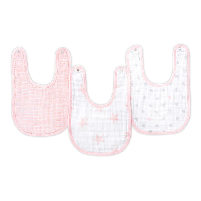 The aden + anais essentials cotton muslin snap bibs 3 pack includes a solid pink bib, a white one with pink stars, and another white featuring pink and gray polka dots.