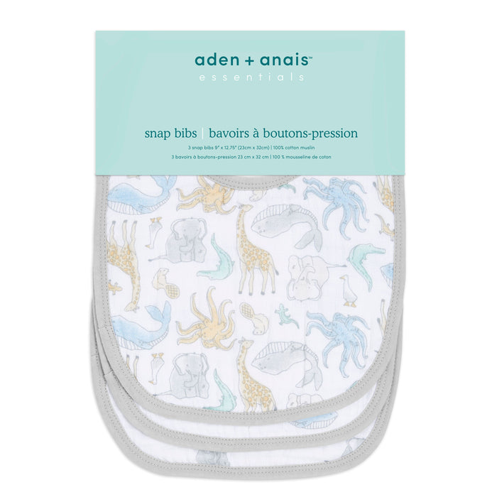 The aden + anais essentials cotton muslin snap bibs 3 pack includes three absorbent bibs with pastel prints of elephants, giraffes, and birds. Designed to grow with your baby, they feature a light gray trim and come in packaging with a light blue label on top.