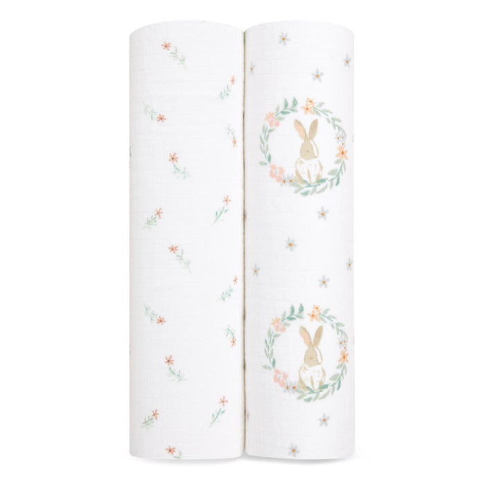 The aden + anais essentials cotton muslin swaddle blanket 2-pack includes two rolled blankets: one with colorful flowers on a white background, and another featuring a rabbit in a floral wreath. Made from soft cotton muslin, they are lightweight and breathable.